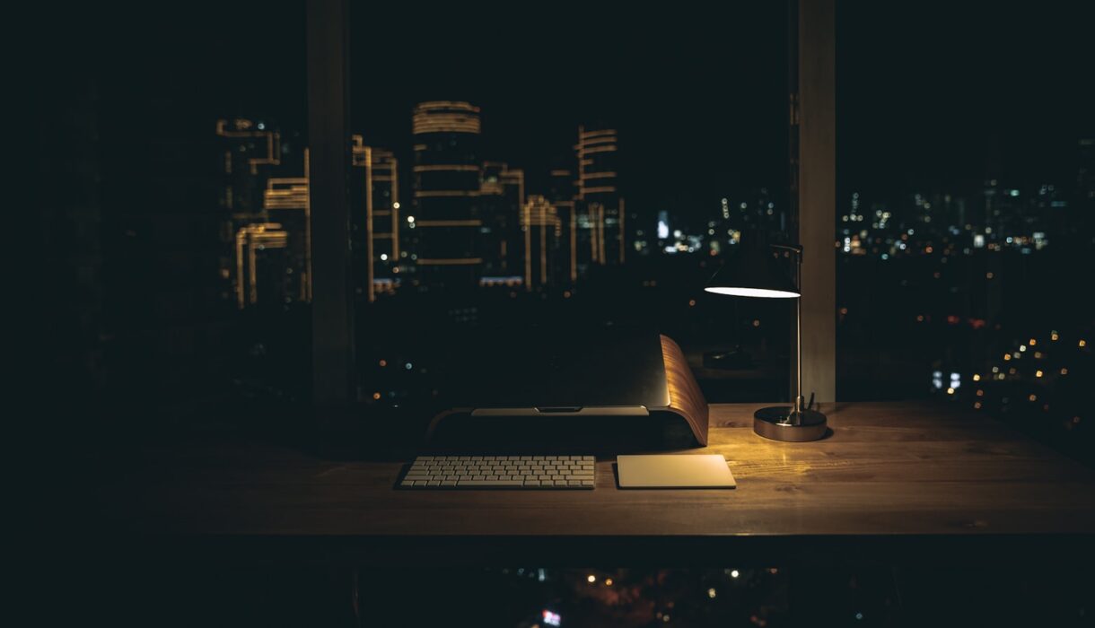 A lit desk lamp on a dark desk