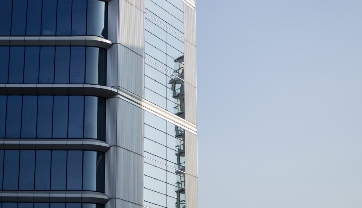 Modern glass office building facade against a clear sky