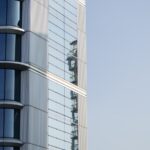 Modern glass office building facade against a clear sky